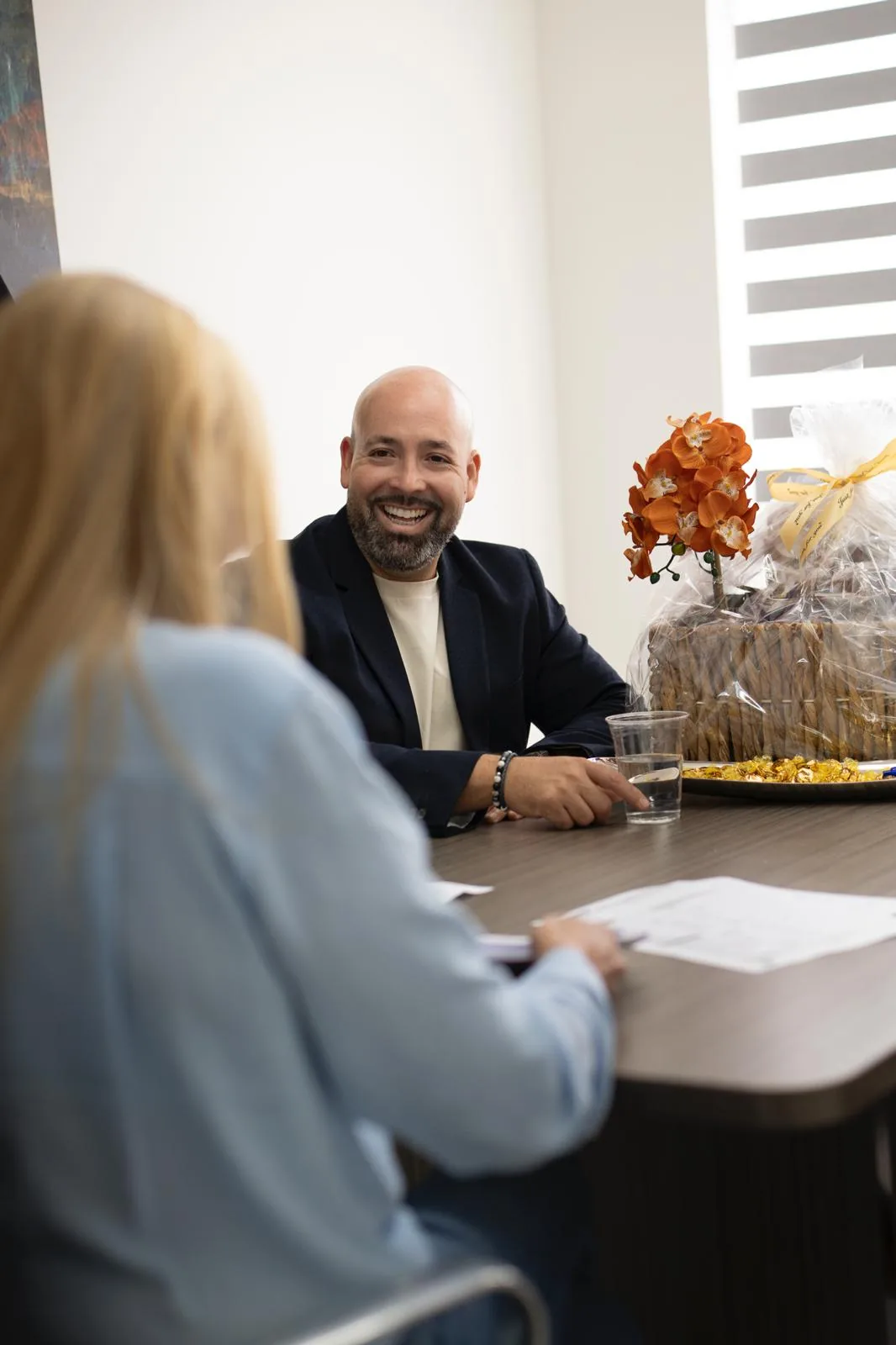 Oscar Baez smiling across the table from a client at his office